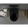 Czarna matowa miska WC z deską wolnoopadającą, obok której znajduje się uchwyt na papier toaletowy oraz stos książek, w tym widoczna książka z napisem "John Ruskin Von Venedig". Ściana i podłoga mają betonową fakturę, a na ścianie zamontowany jest przycisk spłukujący.