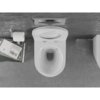 Na zdjęciu znajduje się biała, połyskująca miska WC typu Rimless z deską wolnoopadającą slim, zamontowana na szarej ścianie. Obok widoczny jest uchwyt z rolką papieru toaletowego oraz stos książek, w tym jedna z napisem "John Ruskin Von Venedig".