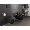 Czarne, matowe WC i bidet zamontowane są na ciemnej, kafelkowej ścianie, obok uchwytu z papierem toaletowym. W tle widoczne są półki z ułożonymi ręcznikami i koszami wiklinowymi.