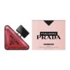 Na zdjęciu widoczny jest trójkątny flakon perfum z napisem "PRADA MILANO" oraz różowe pudełko z czarnym napisem "PARADOXE PRADA RADICAL ESSENCE PARFUM VAPORISATEUR RECHARGEABLE / REFILLABLE SPRAY 90 ml 3 FL. OZ.".