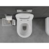 Na zdjęciu widoczna jest biała, połyskująca miska WC typu rimless z deską wolnoopadającą slim, zamontowana na ciemnej ścianie. Obok znajduje się uchwyt z rolką papieru toaletowego oraz kilka książek, w tym jedna z napisem "LIVING HYGGE".
