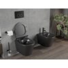 Na zdjęciu znajduje się czarna, matowa miska WC typu rimless z deską wolnoopadającą oraz bidet, oba zamontowane na ścianie wyłożonej szarymi płytkami. Obok miski WC znajduje się uchwyt z papierem toaletowym, a w tle widoczna jest roślina w doniczce.