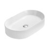 Biała, owalna umywalka nablatowa z ryflowanymi bokami i centralnie umieszczonym odpływem. Produkt ma gładką powierzchnię wewnętrzną i wymiary 49 x 31 cm.