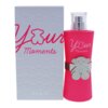 Na zdjęciu widoczna jest różowa butelka perfum z napisem "Your Moments" oraz srebrnym elementem w kształcie misia, obok znajduje się pudełko z tym samym napisem. Na pudełku widnieje również logo "TOUS".
