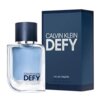 Na zdjęciu widoczna jest butelka perfum z niebieskim płynem oraz ciemnoniebieskie opakowanie z napisem "CALVIN KLEIN DEFY" i informacją "EAU DE TOILETTE SPRAY VAPORISATEUR 1.6 FL OZ 50 ml".