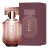 Na zdjęciu widoczny jest flakon perfum o różowym odcieniu z napisem "BOSS THE SCENT LE PARFUM" oraz pudełko w podobnym kolorze z tym samym napisem. Na flakonie znajduje się również napis "HUGO BOSS" na złotej zakrętce, a na pudełku dodatkowo widnieje informacja "50 ml e 1.6 FL. OZ.".