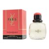 Czerwone pudełko z napisem "Yves Saint Laurent Paris" oraz przezroczysta butelka perfum z czarnym i czerwonym korkiem, na której widnieje złoty napis "PARIS". Na pudełku znajdują się również napisy: "Eau de Toilette", "Vaporisateur - Natural Spray", "2.5 fl. oz." oraz "e 75 ml".