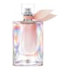 Przezroczysty flakon perfum o iryzującym wykończeniu z różową wstążką przy szyjce. Flakon ma prostokątny kształt z przezroczystym korkiem na górze.