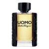 Butelka perfum o pojemności 100 ml z napisem "UOMO Salvatore Ferragamo" na przedniej stronie, z czarnym korkiem i ozdobnymi elementami po bokach. Szkło jest przezroczyste, ukazując jasny płyn wewnątrz.