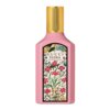 Różowa butelka perfum z złotym korkiem, na której znajduje się etykieta z kwiatowym wzorem i napisem "GUCCI FLORA GORGEOUS GARDENIA".