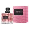 Butelka perfum o fakturze przypominającej kryształ, z czarnym korkiem i etykietą z napisem "VALENTINO", obok różowego pudełka z napisem "VALENTINO DONNA" oraz "BORN IN ROMA". Na dole pudełka widnieje napis "EAU DE PARFUM VAPORISATEUR SPRAY 100 ml 3.4 FL.OZ.".