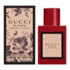 Czerwony flakon perfum z etykietą "GUCCI BLOOM AMBROSIA DI FIORI" stoi obok pudełka ozdobionego czarno-białymi motywami kwiatowymi i motylami. Na pudełku widnieje napis "EAU DE PARFUM INTENSE VAPORISATEUR NATURAL SPRAY" oraz pojemność "30 ml 1.0 FL. OZ".