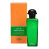 Zielona butelka z czarnym korkiem obok pomarańczowego pudełka z napisem "Eau de basilic pourpre" oraz "Hermes Paris". Na butelce widnieje wytłoczony napis "Cologne Hermes".
