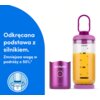 Na zdjęciu znajduje się fioletowy blender personalny z odkręcaną podstawą oraz przezroczysty pojemnik z miarką wypełniony pomarańczowym płynem. Po lewej stronie widoczny jest niebieski panel z tekstem: "Odkręcana podstawa z silnikiem. Zmniejsza wagę w podróży o 50%.*" oraz schematyczna ilustracja blendera.