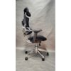 Ergonomiczny fotel biurowy z czarną siatką i chromowaną ramą, posiada regulowane oparcie oraz zagłówek, a także pięcioramienną podstawę z kółkami. Produkt jest ustawiony na neutralnym tle, co podkreśla jego nowoczesny design.