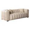 Kremowa, trzyosobowa sofa o pikowanej powierzchni z dwoma poduszkami, ustawiona na ciemnych, prostokątnych nóżkach. Sofa ma elegancki, nowoczesny design z zaokrąglonymi podłokietnikami.