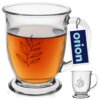 Szklany kubek o pojemności 450 ml z przezroczystego szkła, wypełniony bursztynowym płynem, ozdobiony jest czarnym wzorem przedstawiającym gałązkę z liśćmi. Do uchwytu kubka przymocowana jest etykieta z napisem "orion".