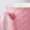 Różowy ceramiczny kubek o pojemności 580 ml z wytłoczonym wzorem serc na powierzchni. Wnętrze kubka jest białe, a uchwyt ma ten sam różowy kolor co reszta kubka.