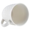 Biały ceramiczny kubek o pojemności 580 ml z wytłoczonym wzorem serc na zewnętrznej powierzchni. Kubek jest ustawiony bokiem, ukazując wnętrze i uchwyt.