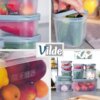 Na zdjęciu widoczne są przezroczyste pojemniki na żywność z niebieskimi pokrywkami, wypełnione różnymi owocami i warzywami, takimi jak truskawki, ogórki, papryki i cebula. Na jednym z pojemników znajdują się symbole wskazujące na możliwość mycia w zmywarce, mrożenia, używania w kuchence mikrofalowej oraz kontaktu z żywnością, a na środku zdjęcia widnieje logo "Vilde".