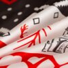 Zbliżenie na materiał pościeli z wzorem w czerwone i czarne elementy, w tym gałązki i geometryczne kształty na białym tle. Tło jest ciemne z białymi kropkami i zygzakami.