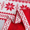 Czerwona narzuta z białym, tłoczonym wzorem świątecznym, przedstawiającym geometryczne gwiazdy i krzyże. Krawędzie narzuty są ozdobione białą lamówką z czerwonym wzorem.