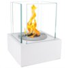 Biały, matowy biokominek wolnostojący o wymiarach 13x13x17 cm z płonącym ogniem, otoczony przezroczystymi szklanymi panelami. Na metalowej podstawie widoczne są dwa okrągłe symbole.