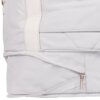 Fragment jasnoszarej torby podróżnej z widocznym zamkiem błyskawicznym i uchwytem z napisem "WINGS". Torba ma prosty, elegancki design z delikatnymi przeszyciami.
