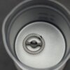 Wnętrze metalowego naczynia z umieszczoną na dnie sprężyną do spieniania. Na ściance widoczne są oznaczenia poziomu maksymalnego i minimalnego.