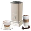 Beżowy spieniacz do mleka z napisem "Vintage Cappuccino" i przyciskiem zasilania na przedniej części, obok filiżanka cappuccino na spodku oraz szklanka latte z pianką i posypką, a także kilka ziaren kawy. Na podstawie urządzenia widoczne jest logo "Ariete