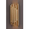 Dekoracyjny kinkiet ścienny złożony z pionowych, złotych tub, emitujący ciepłe światło.