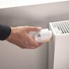 Na zdjęciu widoczna jest ręka trzymająca głowicę termostatyczną NETATMO Valves Set Wi-Fi, która jest przymocowana do grzejnika. Na głowicy wyświetlana jest liczba "19".