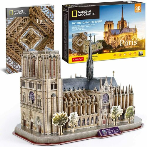 Na zdjęciu znajduje się model 3D katedry Notre Dame, wykonany z puzzli, z widocznymi detalami architektonicznymi i drzewami wokół. W tle widoczne są dwa opakowania z napisami: "National Geographic", "Paris" oraz "Notre-Dame de Paris", a także logo "CubicF