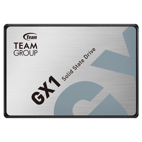 Na zdjęciu widoczny jest dysk SSD z napisem "TEAM GROUP GX1 Solid State Drive" na srebrnym tle z dużymi literami "GX" w tle. Logo "Team" znajduje się w lewym górnym rogu.