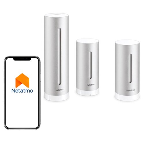 Na zdjęciu widoczny jest zestaw trzech cylindrycznych urządzeń w kolorze srebrnym z białymi podstawami, każde z logo "Netatmo" na dole. Obok nich znajduje się smartfon z wyświetlonym logo "Netatmo" na ekranie.