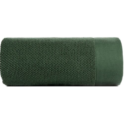 Na zdjęciu znajduje się zwinięty ręcznik w kolorze butelkowej zieleni o wymiarach 30 x 50 cm. Powierzchnia ręcznika ma teksturę z drobnymi pętelkami.