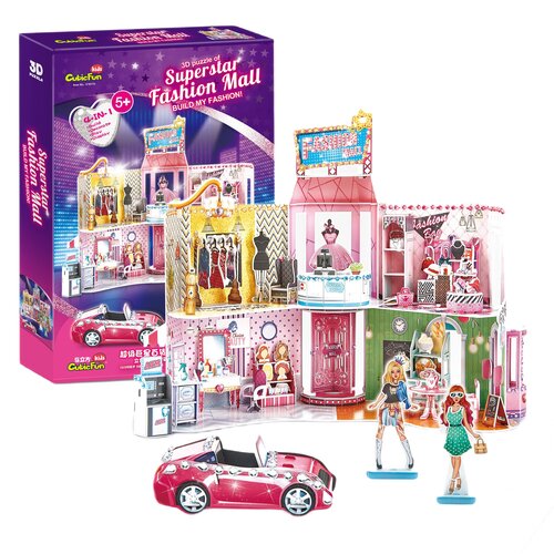 Pudełko przedstawia zestaw puzzli 3D o nazwie "Superstar Fashion Mall" z kolorową grafiką centrum handlowego i napisem "Build My Fashion!". Obok pudełka znajduje się złożony model centrum handlowego z różnymi sklepami, różowym samochodem i dwoma postaciam