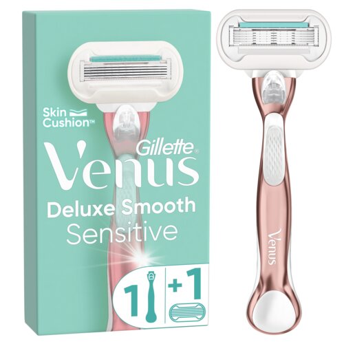 Na zdjęciu znajduje się różowo-złota golarka z białą głowicą oraz opakowanie w kolorze miętowym z napisem "Gillette Venus Deluxe Smooth Sensitive" i symbolem "1 + 1". Na opakowaniu widoczny jest również napis "Skin Cushion".