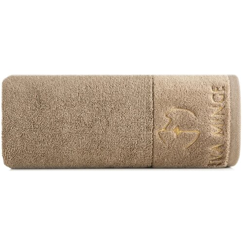 Beżowy ręcznik o wymiarach 30 x 50 cm, z widocznym haftem przedstawiającym logo i napisem "EVA MINGE" w kolorze złotym. Ręcznik ma teksturę frotte i jest zwinięty w rolkę.