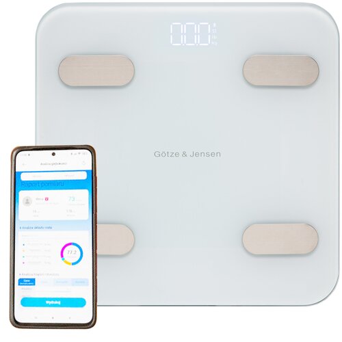 Biała waga łazienkowa Götze & Jensen z czterema metalowymi sensorami i wyświetlaczem pokazującym "0.00" kg, obok której znajduje się smartfon z aplikacją wyświetlającą raport pomiaru. Na wadze widoczne jest logo "Götze & Jensen".