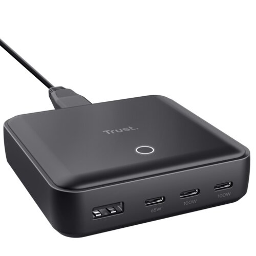 Czarny zasilacz do laptopa z logo "Trust" na górze, posiadający cztery porty: jeden USB oznaczony jako 65W, dwa porty USB-C oznaczone jako 100W oraz jeden port USB-A. Na powierzchni znajduje się okrągły wskaźnik świetlny.