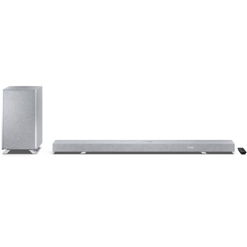 Na zdjęciu znajduje się srebrny soundbar oraz bezprzewodowy subwoofer, oba o prostym, nowoczesnym designie. Obok soundbara leży mały, czarny pilot.
