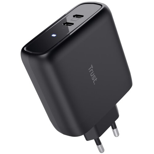 Czarny zasilacz do laptopa z dwoma portami USB-C i widocznym logo "Trust" na obudowie. Na górnej części urządzenia świeci się mała, niebieska dioda.