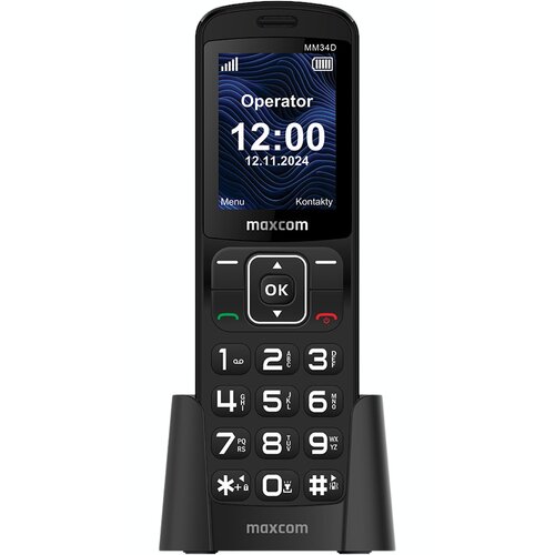 Czarny telefon komórkowy z dużymi przyciskami numerycznymi i ekranem wyświetlającym godzinę 12:00 oraz datę 12.11.2024. Na ekranie widoczne są również napisy: "Operator", "Menu", "Kontakty", a poniżej logo "maxcom".