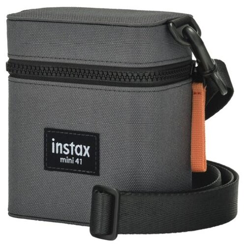 Szary futerał z czarnym zamkiem błyskawicznym i czarnym paskiem, z widocznym napisem "instax mini 41" na przodzie. Obok futerału znajduje się pomarańczowy element.