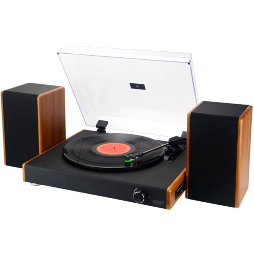 Gramofon z drewnianymi elementami obudowy, z przezroczystą pokrywą, na której znajduje się czarny winyl z czerwonym środkiem; obok znajdują się dwa głośniki. Na froncie gramofonu widoczny jest napis "ADLER".