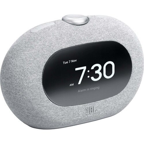 Szary radiobudzik z wyświetlaczem pokazującym datę "Tue 7 Nov" i godzinę "7:30 AM" oraz napis "Alarm is ringing". Na obudowie widoczne jest logo "JBL".