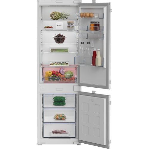 Lodówka BEKO B3BCNA294HS jest otwarta, ukazując wnętrze z różnorodnymi produktami spożywczymi, takimi jak ananas, jajka, butelki z napojami, warzywa i owoce. Na półkach drzwi widoczne są napisy "Harvestr" i "AeroFlow".
