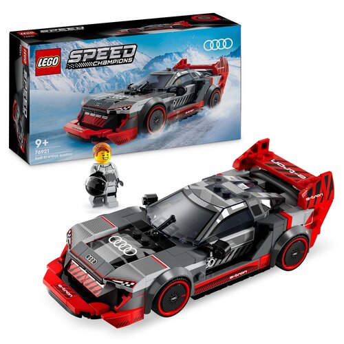 Zestaw LEGO przedstawia model wyścigowego samochodu Audi S1 E-tron Quattro z serii Speed Champions, z widocznym logo Audi na masce. Obok samochodu znajduje się figurka ludzika LEGO w kasku, a w tle pudełko z grafiką przedstawiającą samochód na tle górskie
