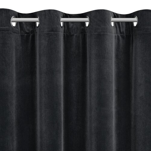 Czarna zasłona z materiału o aksamitnej fakturze, zawieszona na metalowym karniszu z okrągłymi przelotkami. Produkt to "Zasłona EUROFIRANY Nita 140 x 250 cm Czarny".